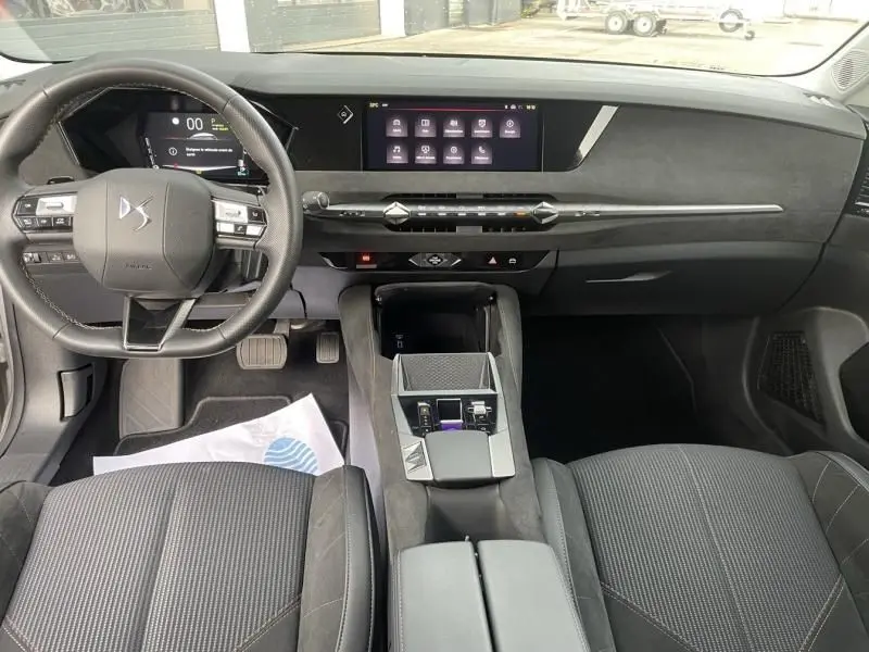 Intérieur du DS4 Hybride E-Tense 2023 vu de face, tableau de bord moderne avec écran tactile et volant multifonction noir.