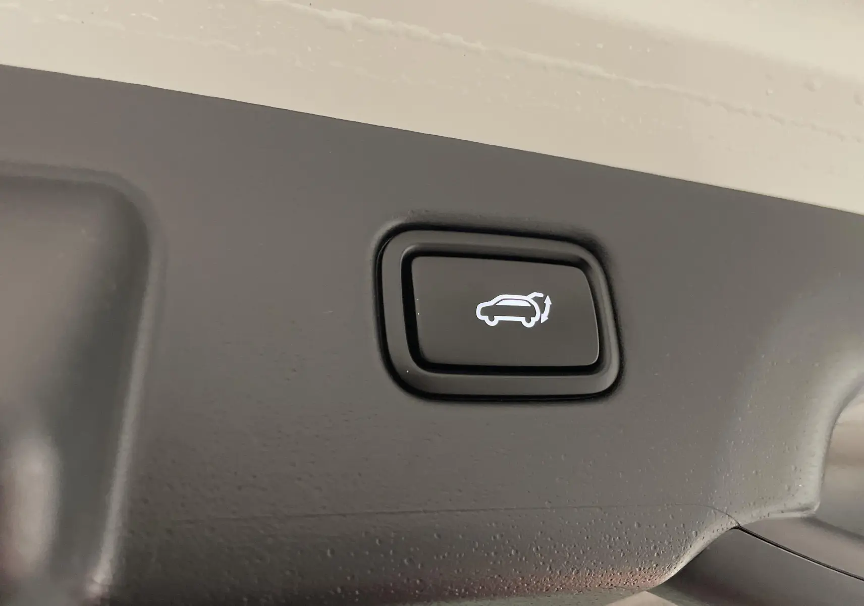 Bouton d'ouverture électrique du hayon sur le coffre intérieur d'un Kia Niro blanc hybride 2025.