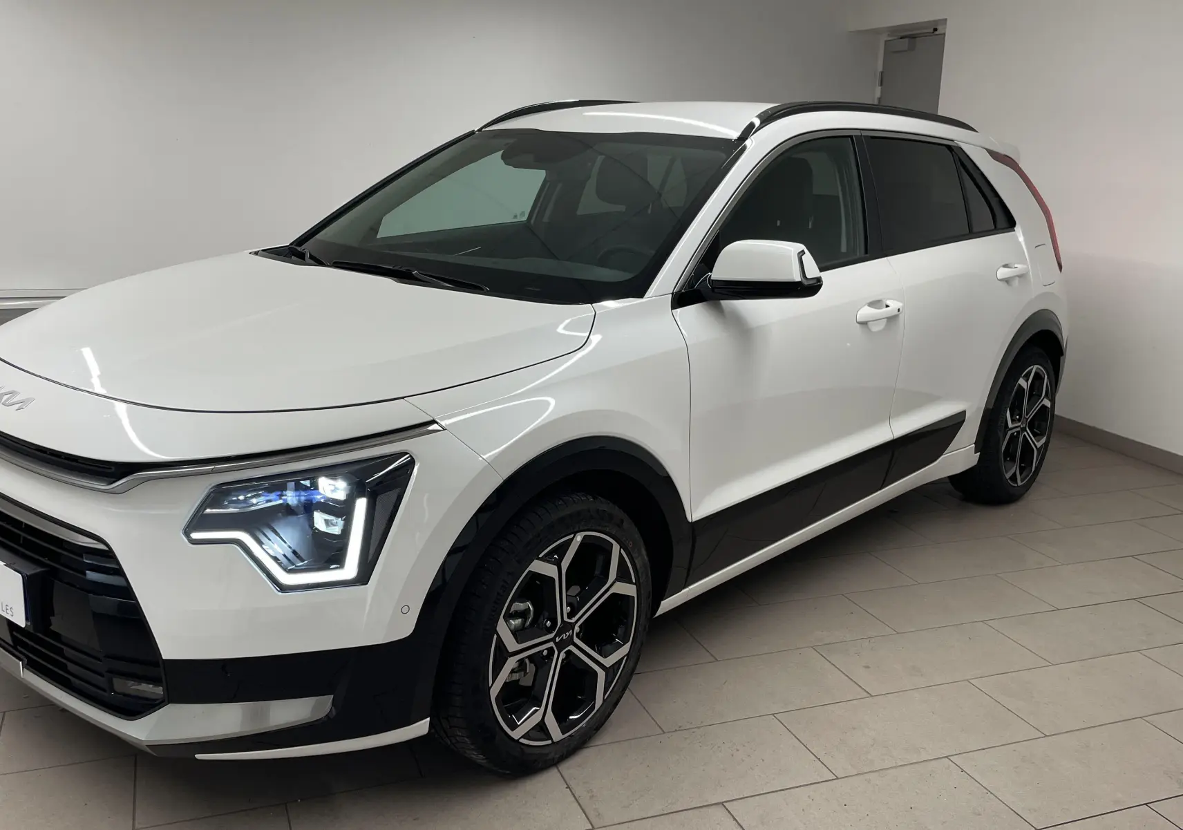 KIA NIRO 2025 blanc vue 3/4 avant droit avec phares LED et jantes alliage distinctives.