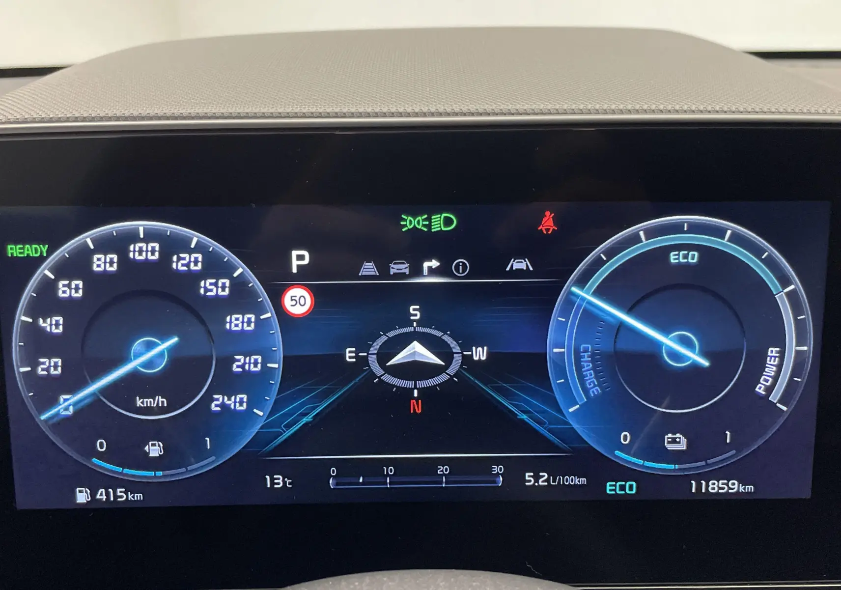 Tableau de bord numérique du Kia Niro blanc 2025, affichant vitesse, autonomie, consommation et mode ECO.