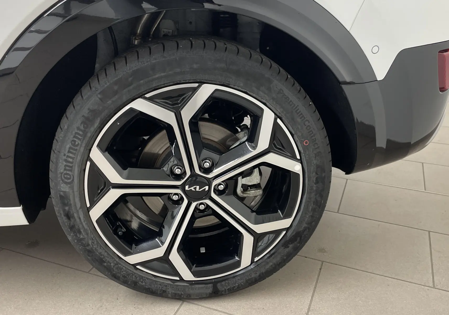 Gros plan sur la roue arrière droite blanche du KIA NIRO 2025 avec jante noire et argent au design géométrique.