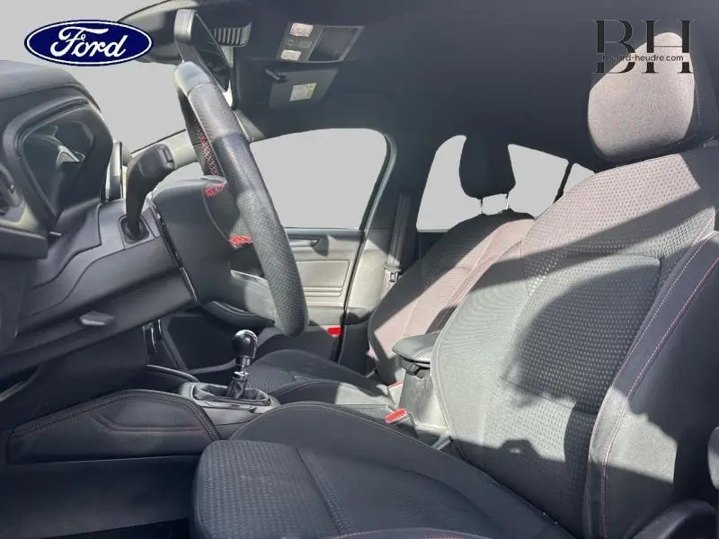 Intérieur avant de la Ford Focus 2019 noir Shadow, vue côté conducteur montrant sièges tissu noir avec surpiqûres rouges et volant cuir sport.
