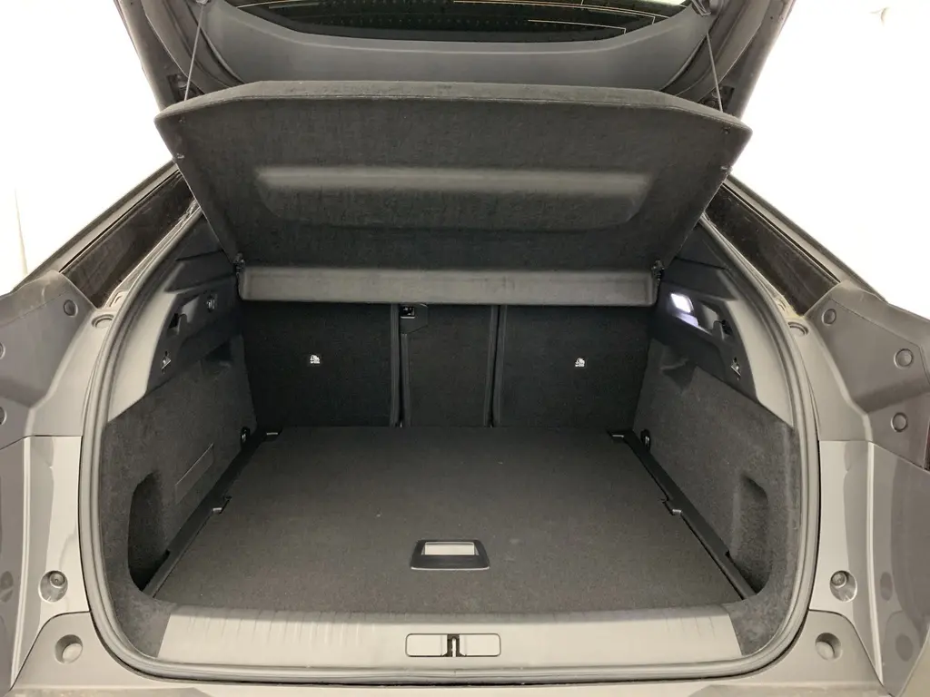 Coffre ouvert vu de l'arrière du Peugeot 3008 Hybrid gris titane avec intérieur noir et hayon motorisé.
