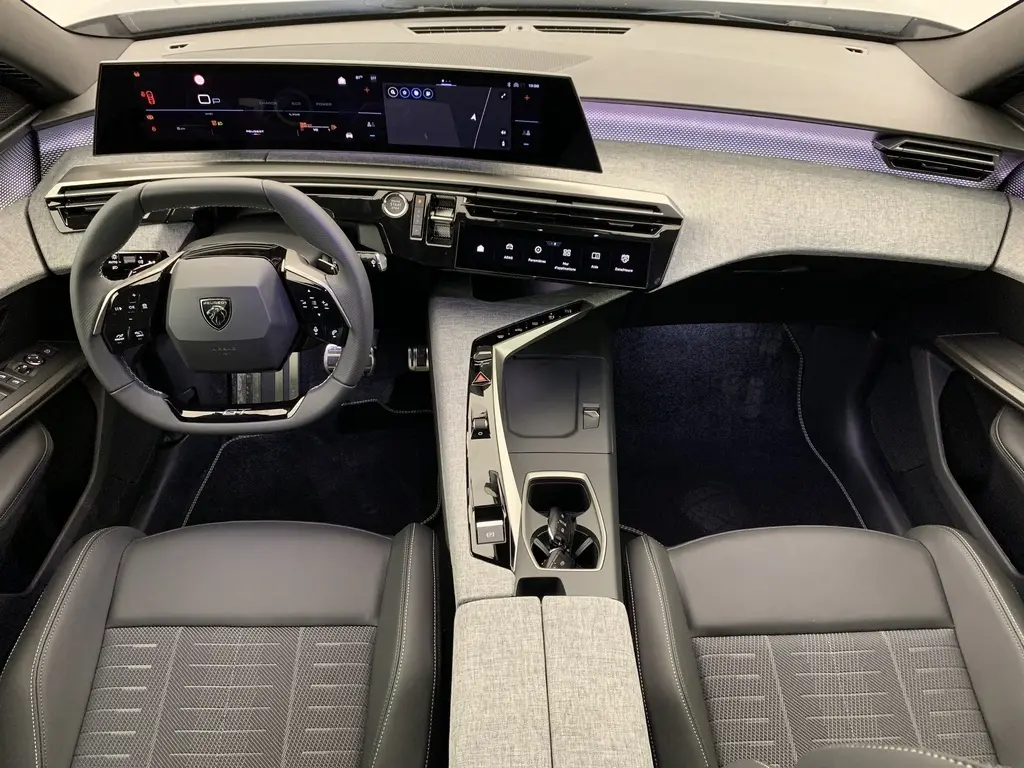 Vue intérieure avant du Peugeot 3008 Hybrid 145 GT, planche de bord grise avec éclairage d'ambiance violet et volant compact noir.