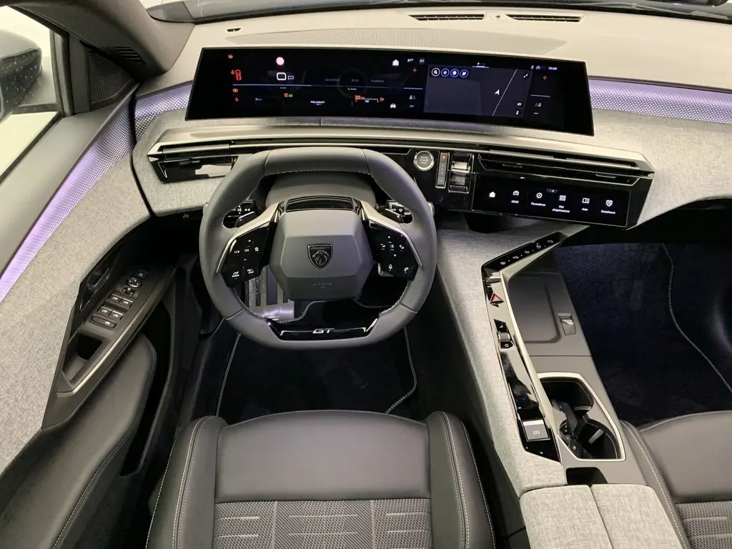 Vue intérieure frontale du Peugeot 3008 Hybrid GT 2025, tableau de bord numérique panoramique et volant compact cuir noir GT.