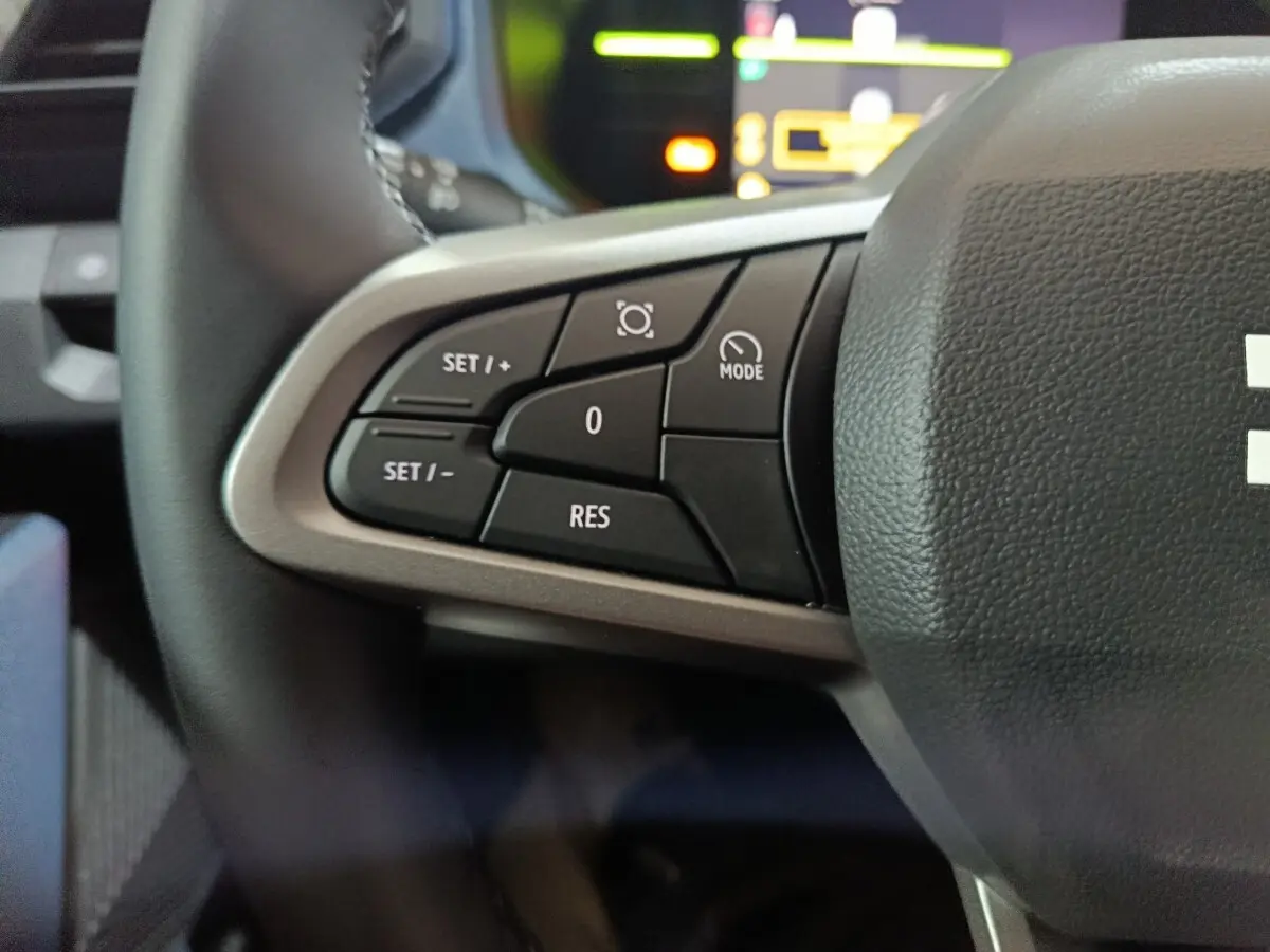 Gros plan sur les commandes de régulateur de vitesse au volant d’un Dacia Bigster gris foncé, intérieur moderne.