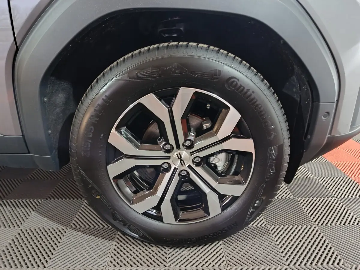 Gros plan sur la roue avant droite du Dacia Bigster gris foncé, avec jante alliage noire et argentée au design moderne.