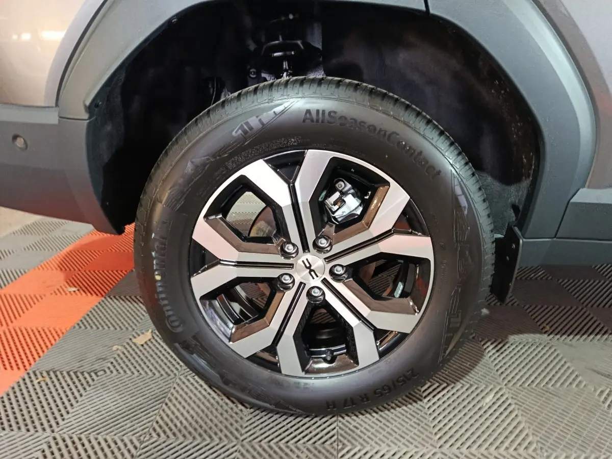 Gros plan sur la roue avant droite du Dacia Bigster gris foncé, mettant en valeur la jante alliage bicolore et le pneu Continental.