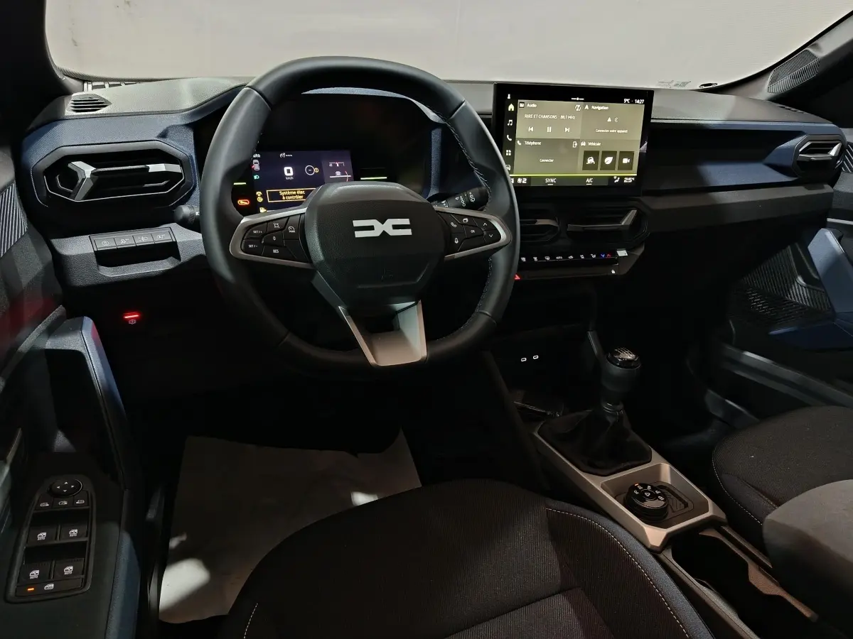 Vue intérieure centrée sur le tableau de bord et volant du Dacia Bigster gris foncé, avec écran tactile et boîte manuelle.