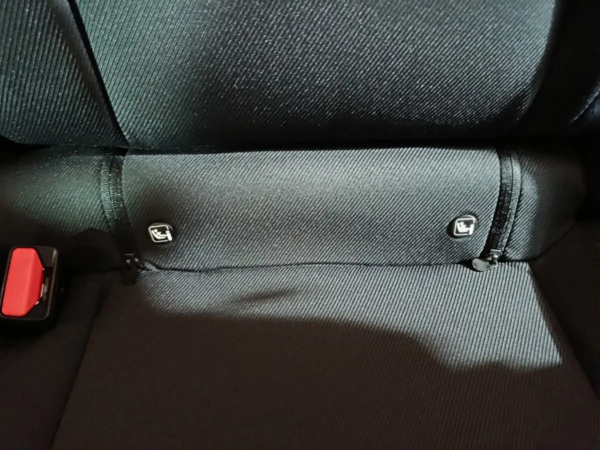 Gros plan sur la banquette arrière noire du Dacia Bigster 2025, montrant les fixations Isofix et une boucle de ceinture rouge.