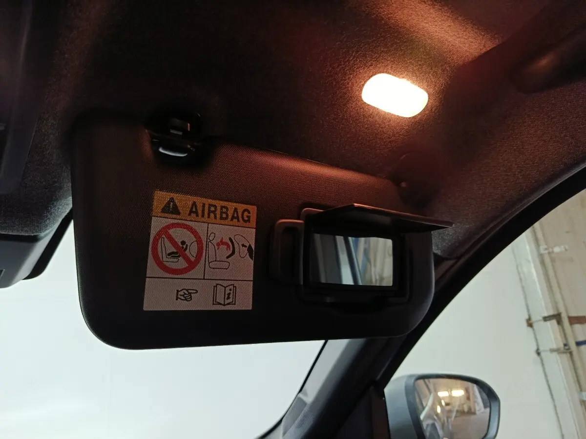 Détail du pare-soleil côté conducteur avec miroir ouvert et avertissement airbag dans un Dacia Bigster gris foncé.