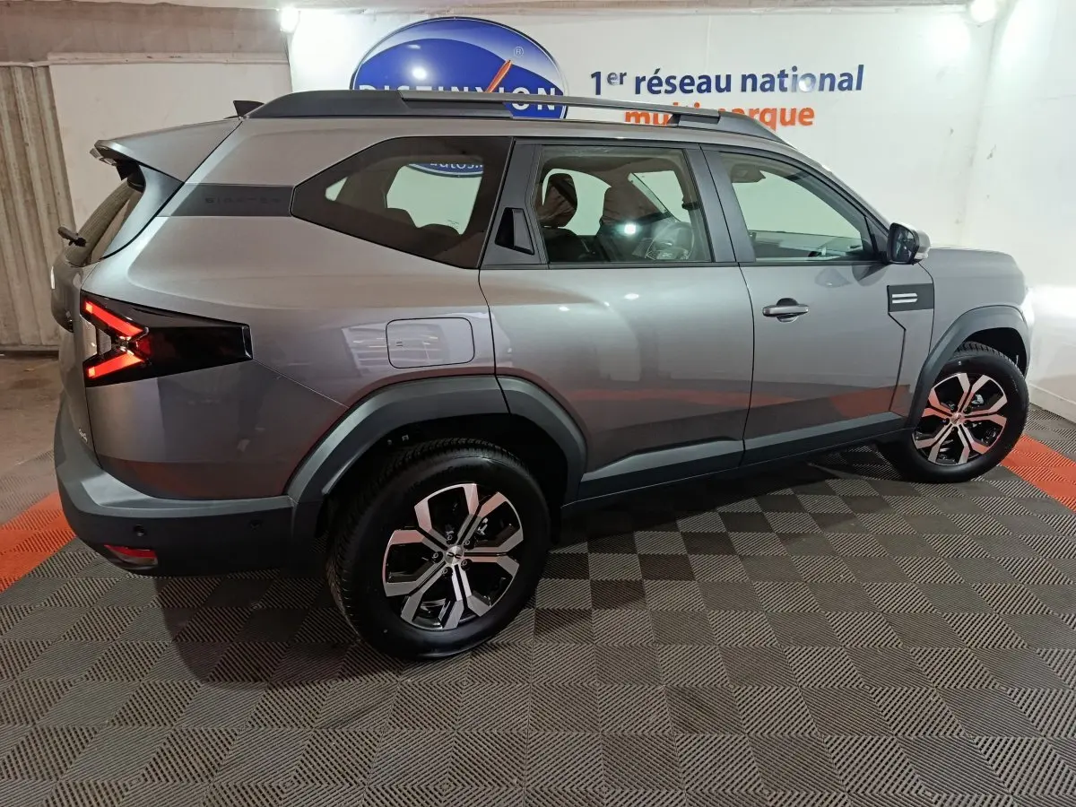 Vue côté droit en 3/4 arrière d'un Dacia Bigster gris foncé avec jantes alliage et feux arrière LED distinctifs.