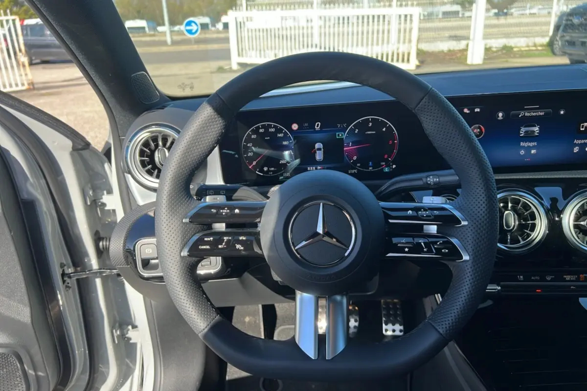 Vue intérieure frontale du volant cuir multifonctions de la Mercedes Classe A 200D BVA Exclusive Design avec tableau de bord digital.