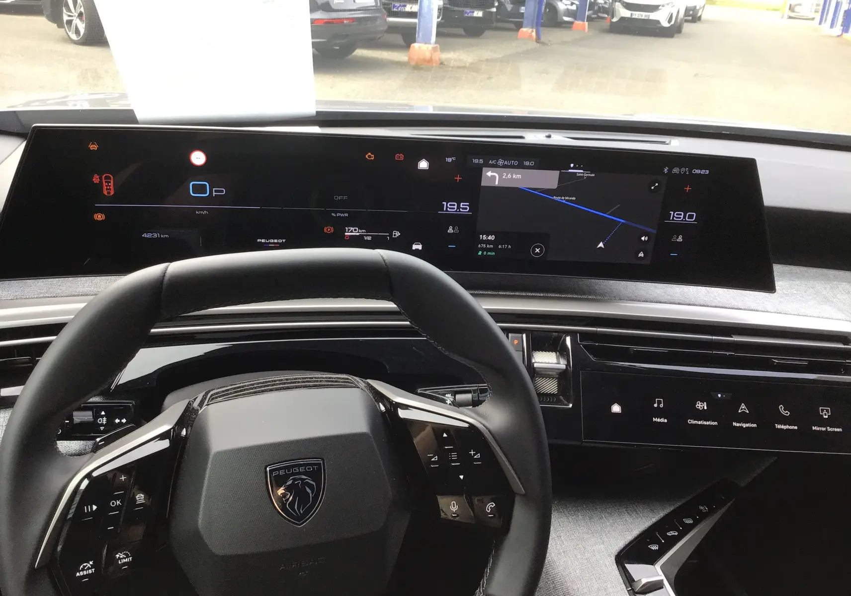 Vue intérieure centrée sur le volant et le tableau de bord numérique du Peugeot 3008 1.2 Hybrid 145 gris Artense, avec écran tactile et navigation.