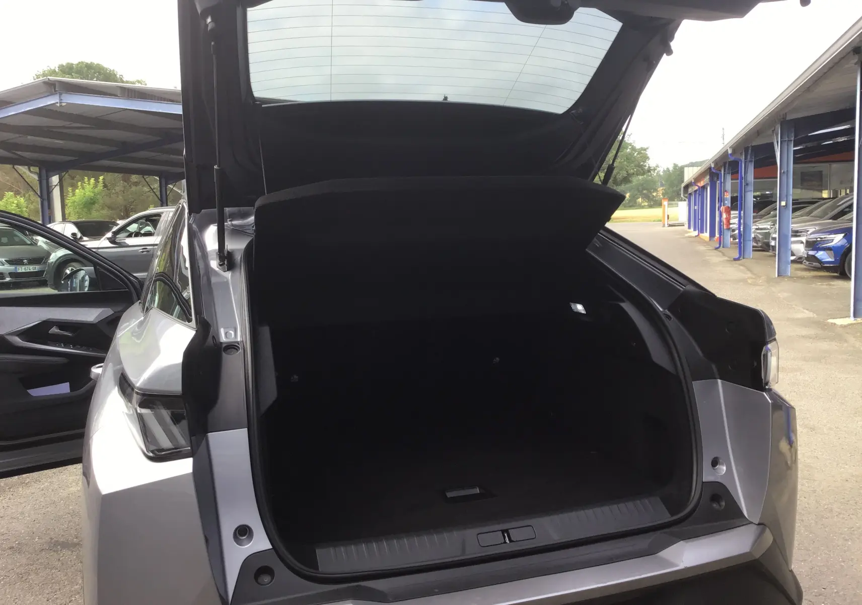 Vue arrière du Peugeot 3008 gris Artense 2026 avec coffre ouvert, montrant l’espace de chargement vide et la porte arrière levée.
