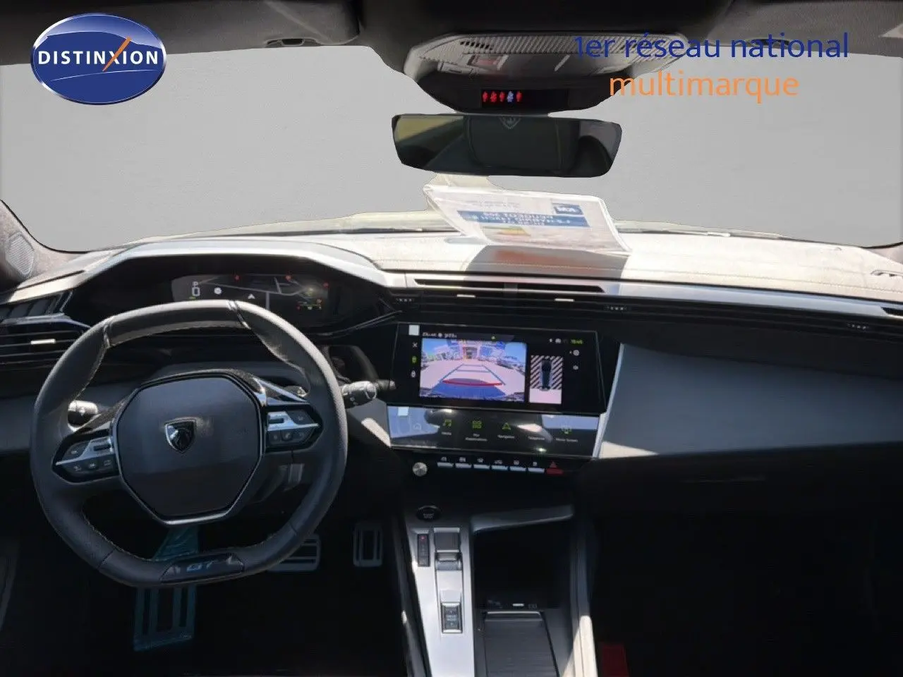 Vue intérieure du tableau de bord et volant noir de la Peugeot 308 Hybrid 145ch GT avec écran tactile et caméra de recul affichée.