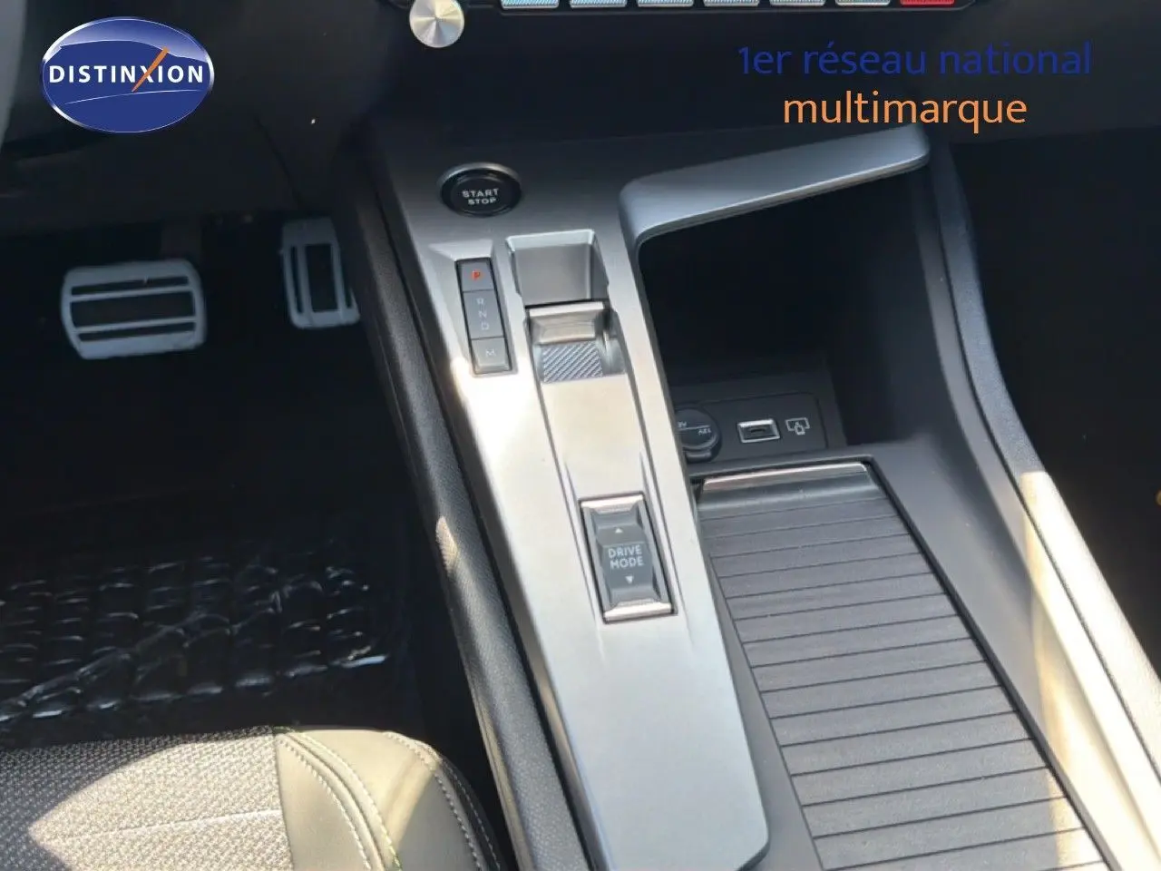 Vue rapprochée de la console centrale de la Peugeot 308 Hybrid 145ch GT 2026 avec levier de vitesses et bouton Drive Mode.
