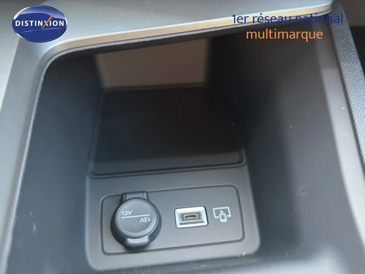 Gros plan intérieur sur la prise 12V et port USB dans le rangement central de la Peugeot 308 Hybrid 145ch GT noir perle métal.