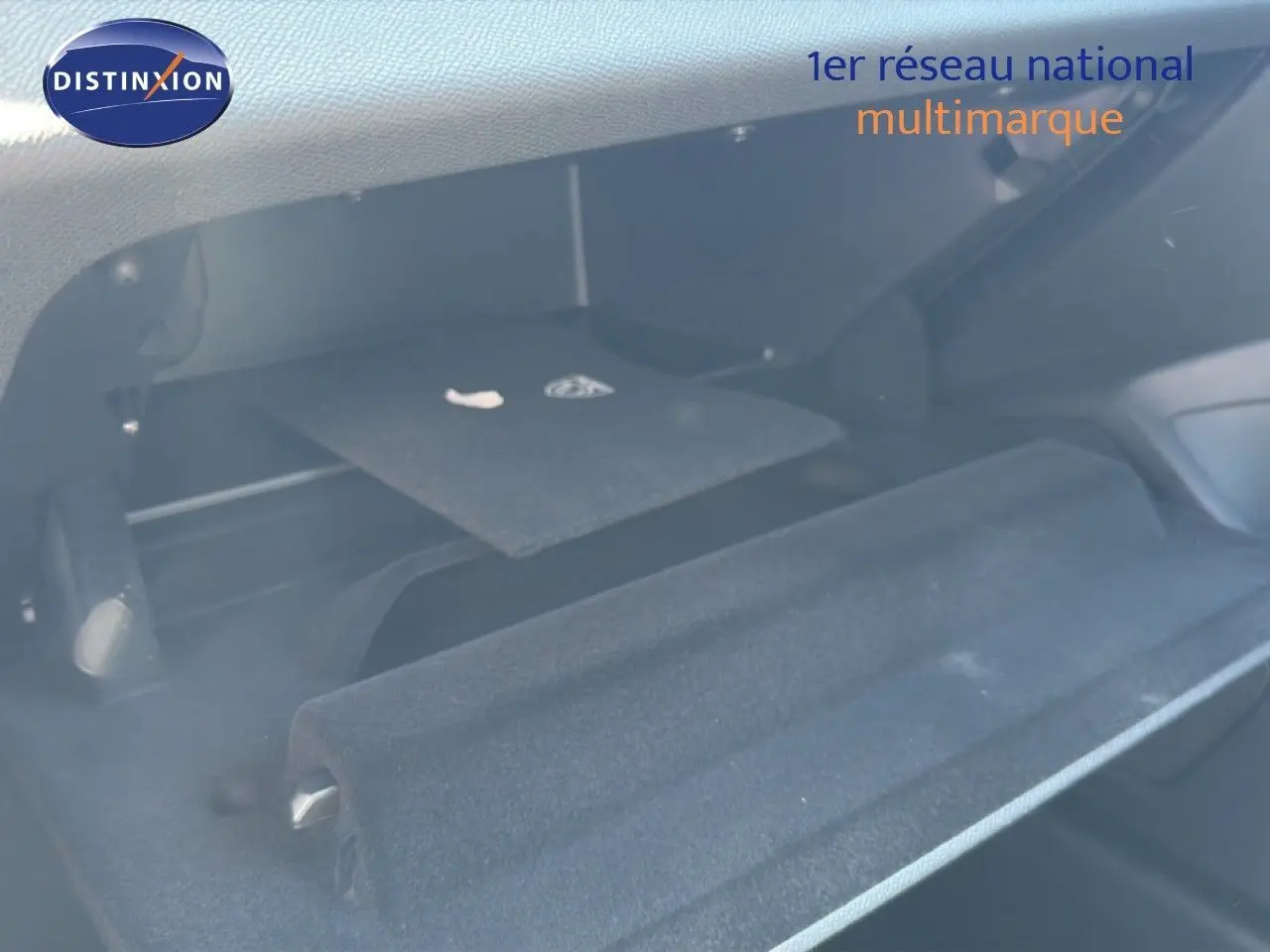 Coffre ouvert de la Peugeot 308 Hybrid 145ch GT 2026 en noir perle métal, montrant la moquette et un rangement intérieur.