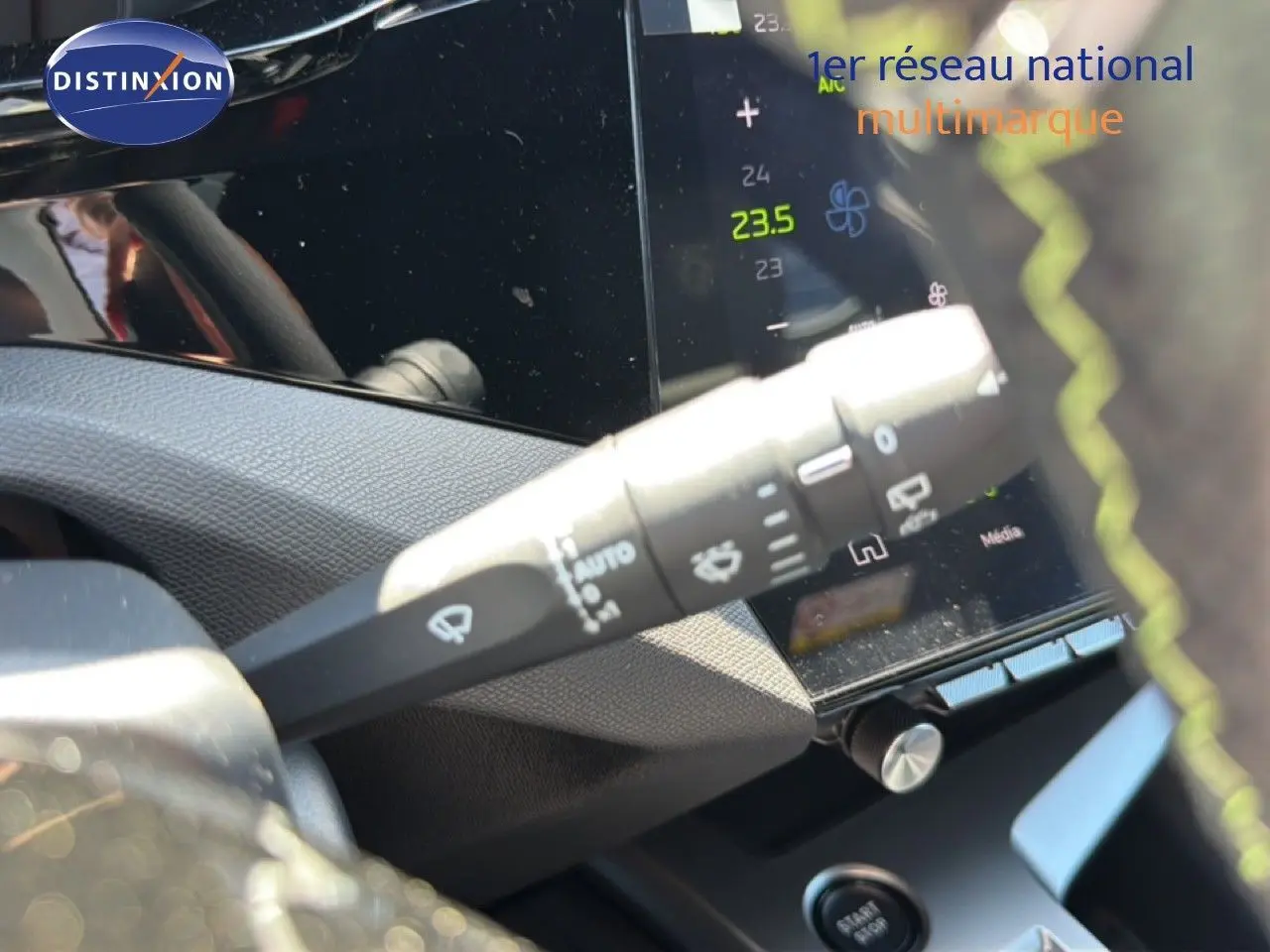 Gros plan sur la commande d’essuie-glace à gauche du volant d’une Peugeot 308 Hybrid noir perle métal, intérieur moderne.