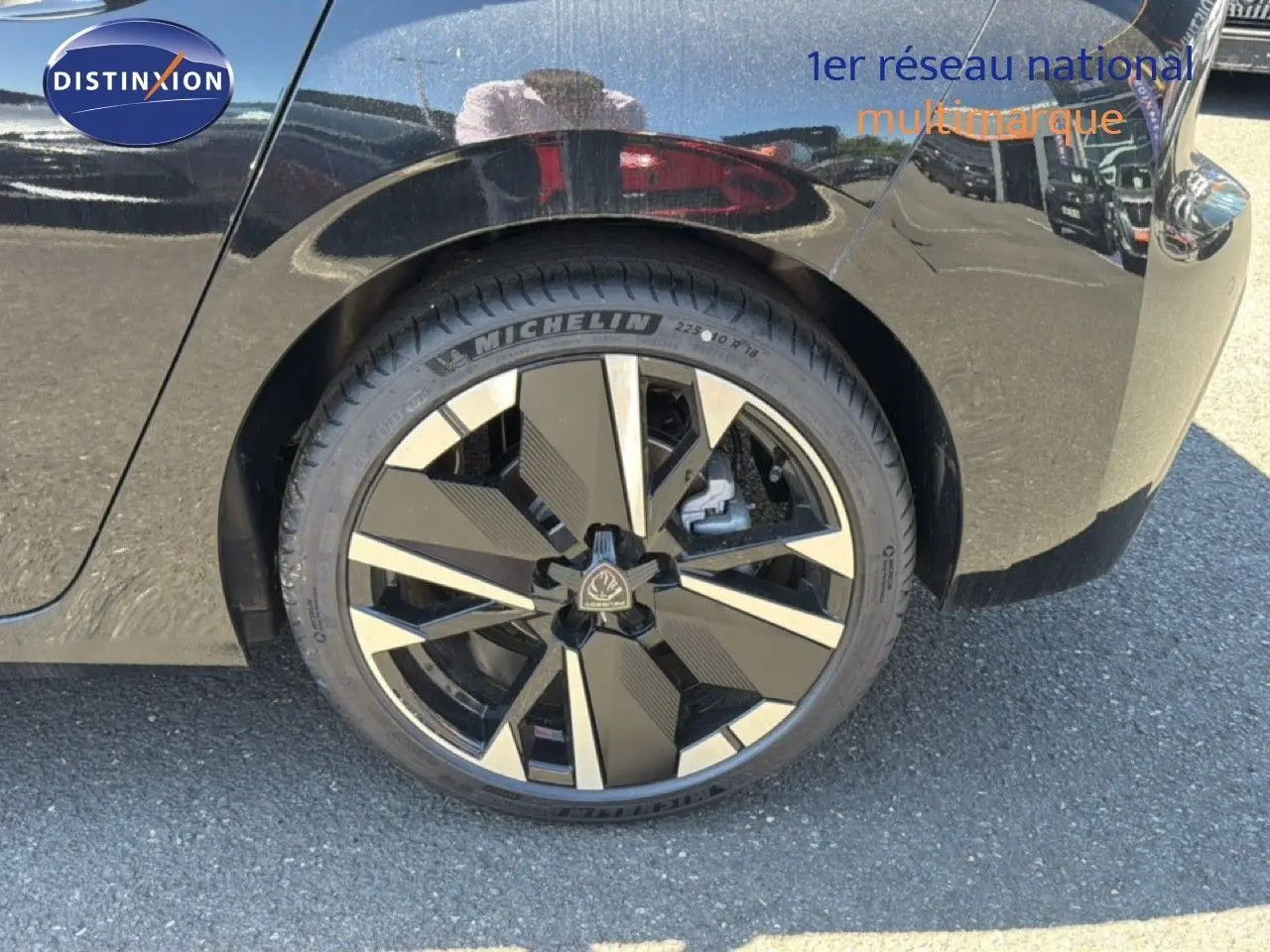 Gros plan sur la roue arrière droite d'une Peugeot 308 Hybrid 145ch GT noir perle métal avec jante moderne bicolore.