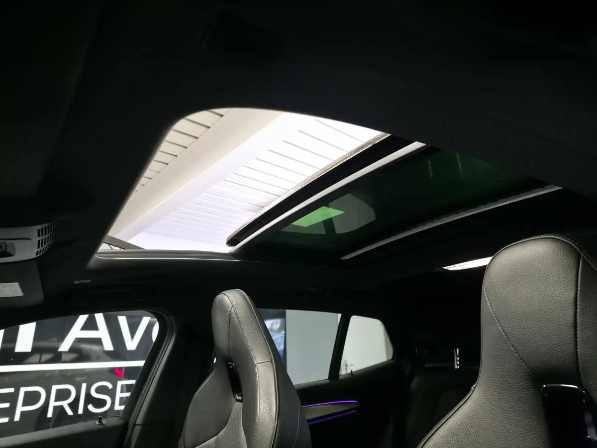 Vue intérieure du toit ouvrant panoramique et des sièges avant en cuir noir du BMW X2 sDrive 18d M Sport 2023.