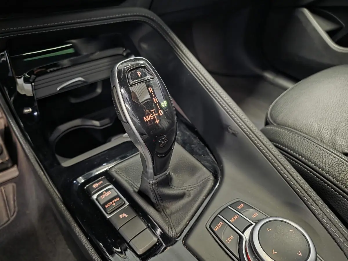 Gros plan sur la console centrale noire du BMW X2 M Sport 2023, avec levier de vitesses automatique et commandes de mode de conduite.
