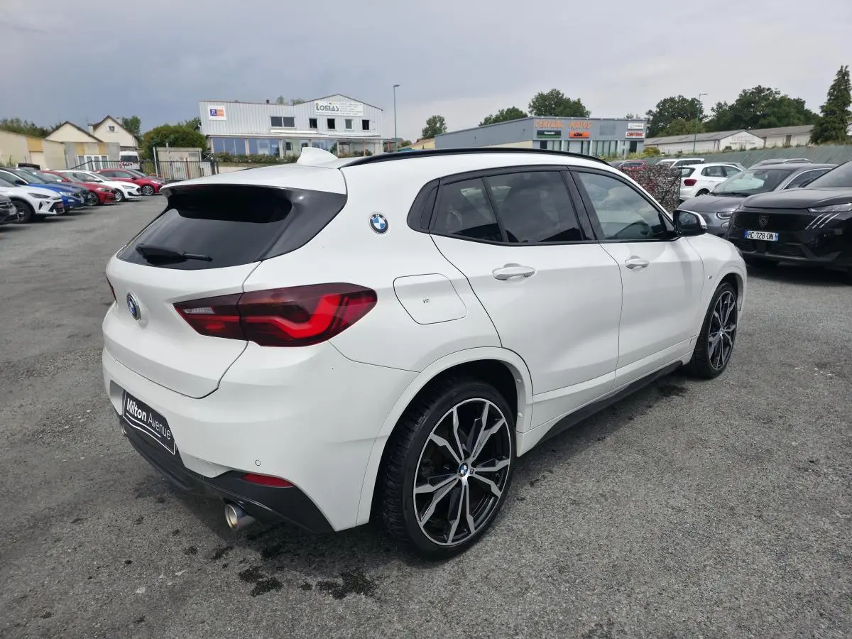 BMW X2 sDrive 18d M Sport blanc vue 3/4 arrière droit avec jantes alliage 20 pouces et toit noir panoramique.