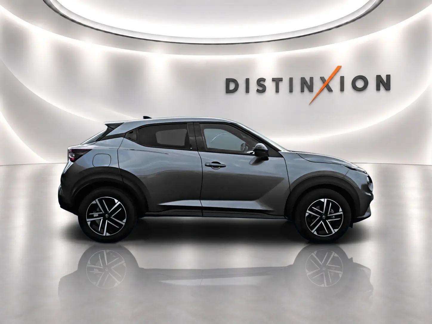Profil droit du Nissan Juke gris 2025 avec jantes alliage noires et toit noir dans un studio lumineux.