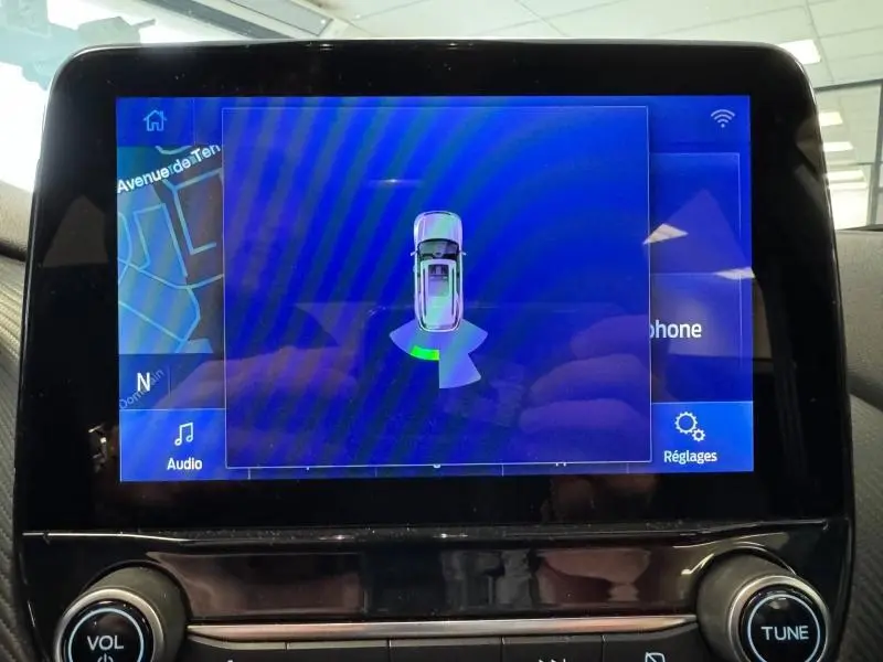 Écran tactile du système multimédia montrant l'assistance au stationnement du Ford Puma blanc Glacier.