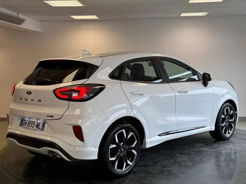 Vue 3/4 arrière droite du Ford Puma blanc Glacier 2022 avec jantes alliage noires et feux arrière LED allumés.