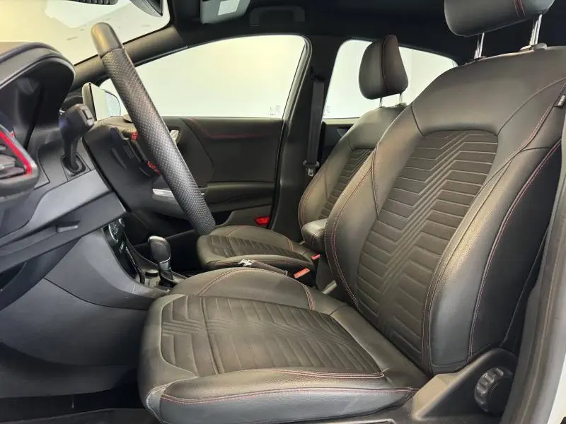 Vue intérieure côté conducteur du Ford Puma 2022, sièges cuir noir avec surpiqûres rouges et volant sport multifonction.