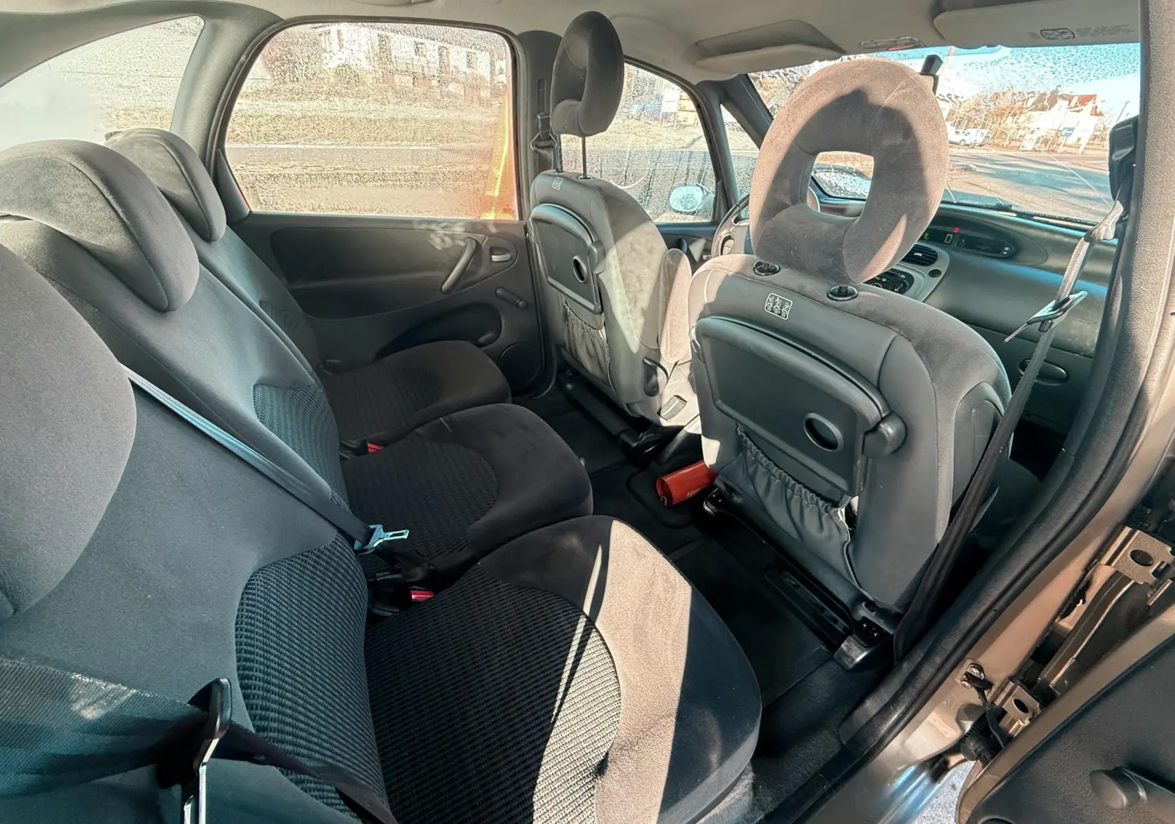 Vue intérieure arrière droite du Citroën Xsara Picasso 2009, sièges tissu noir et dossier avant avec tablette intégrée.