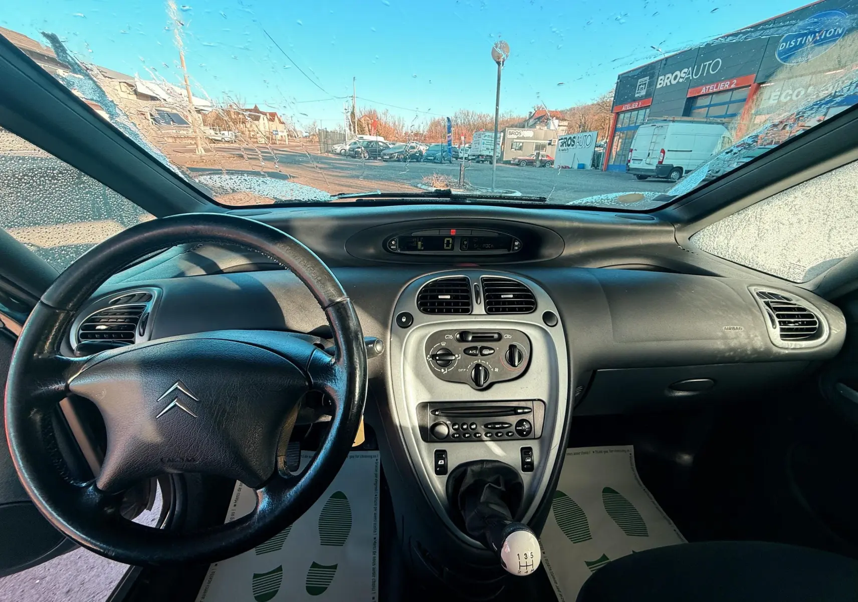 Vue intérieure du tableau de bord noir et volant cuir d'une Citroën Xsara Picasso 1.6 HDi 2009 avec levier de vitesses manuel.