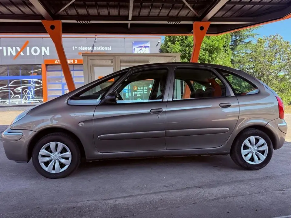Vue de profil côté gauche d'une Citroën Xsara Picasso beige de 2009 stationnée sous un abri.