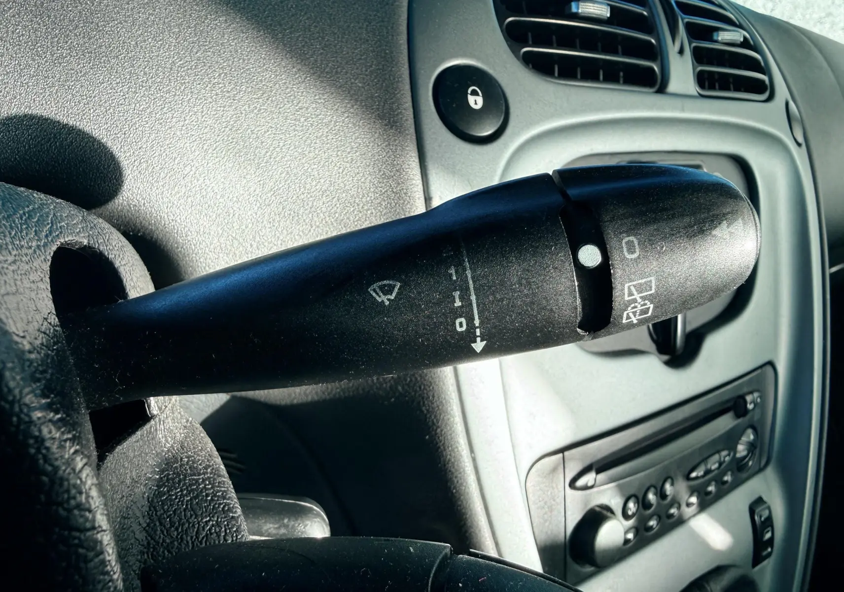 Gros plan sur la commande d’essuie-glace côté gauche du tableau de bord gris clair d’une Citroën Xsara Picasso.