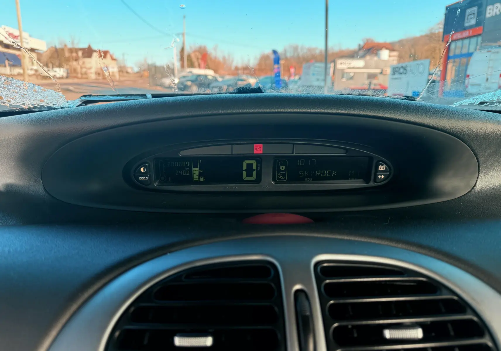 Vue rapprochée du tableau de bord numérique du Citroën Xsara Picasso 2009, affichage central et aérateurs noirs.