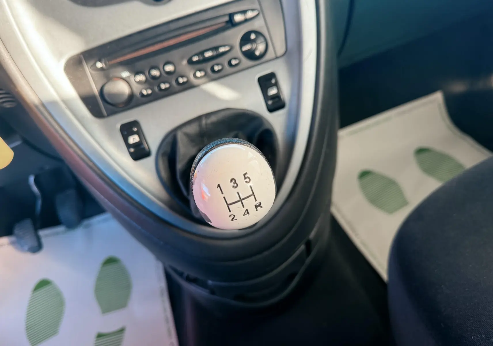 Gros plan sur le levier de vitesses manuel blanc au centre de la console d’une Citroën Xsara Picasso beige de 2009.