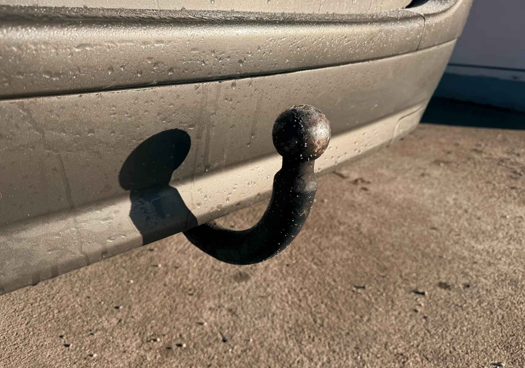 Gros plan sur l'attelage d'une Citroën Xsara Picasso beige, visible sur le pare-chocs arrière côté droit.