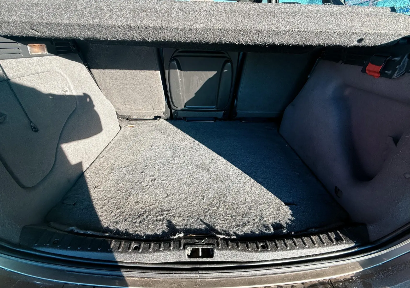 Vue intérieure du coffre beige du Citroën Xsara Picasso 2009, montrant l'espace de chargement et la moquette usée.