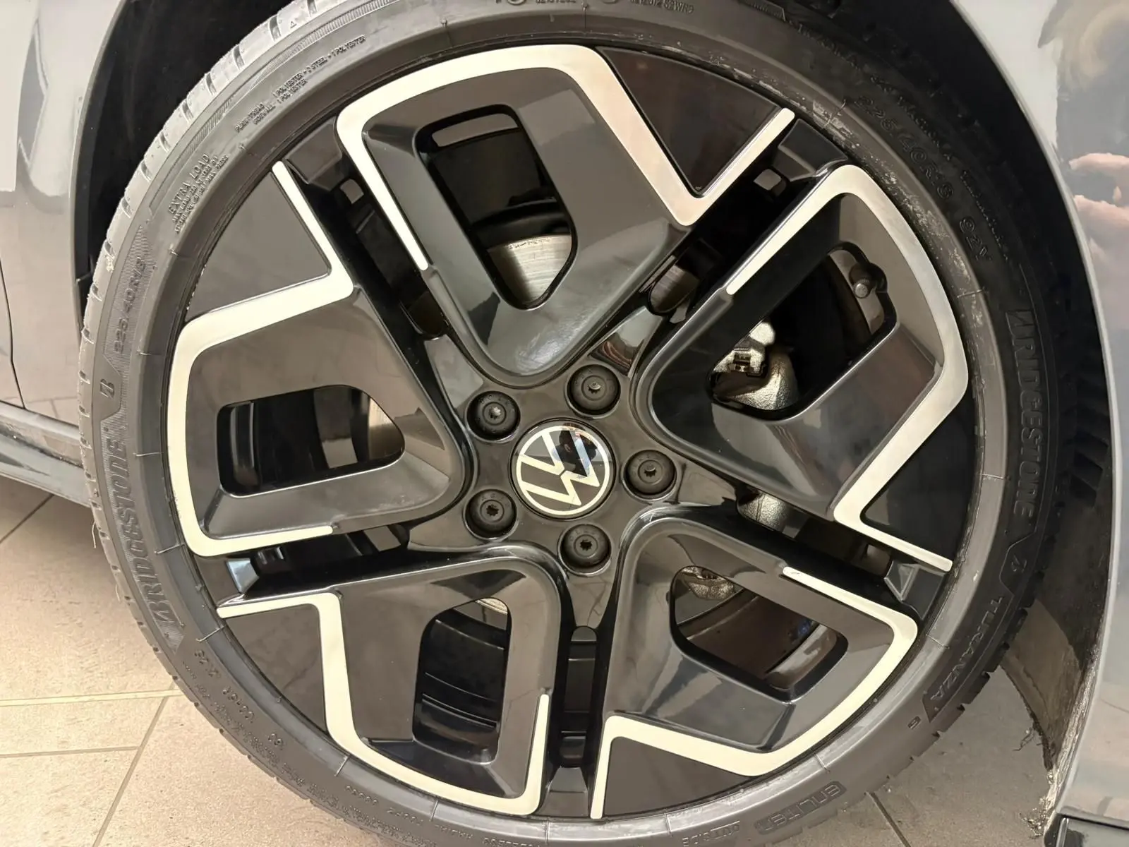 Gros plan sur la jante avant droite noire et argentée d'une Volkswagen Golf Gris Dauphin 2025 R-Line Edition.