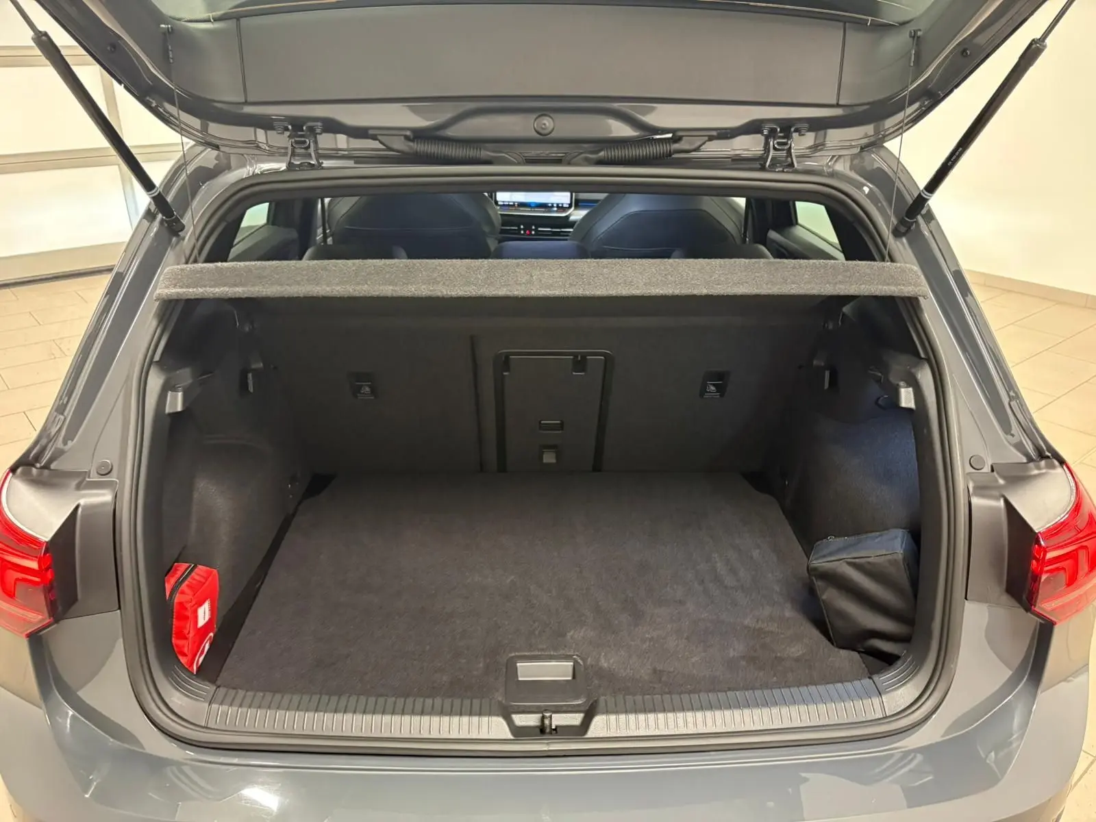 Coffre ouvert vu de l'arrière d'une Volkswagen Golf gris dauphin, avec cache-bagages et intérieur spacieux.
