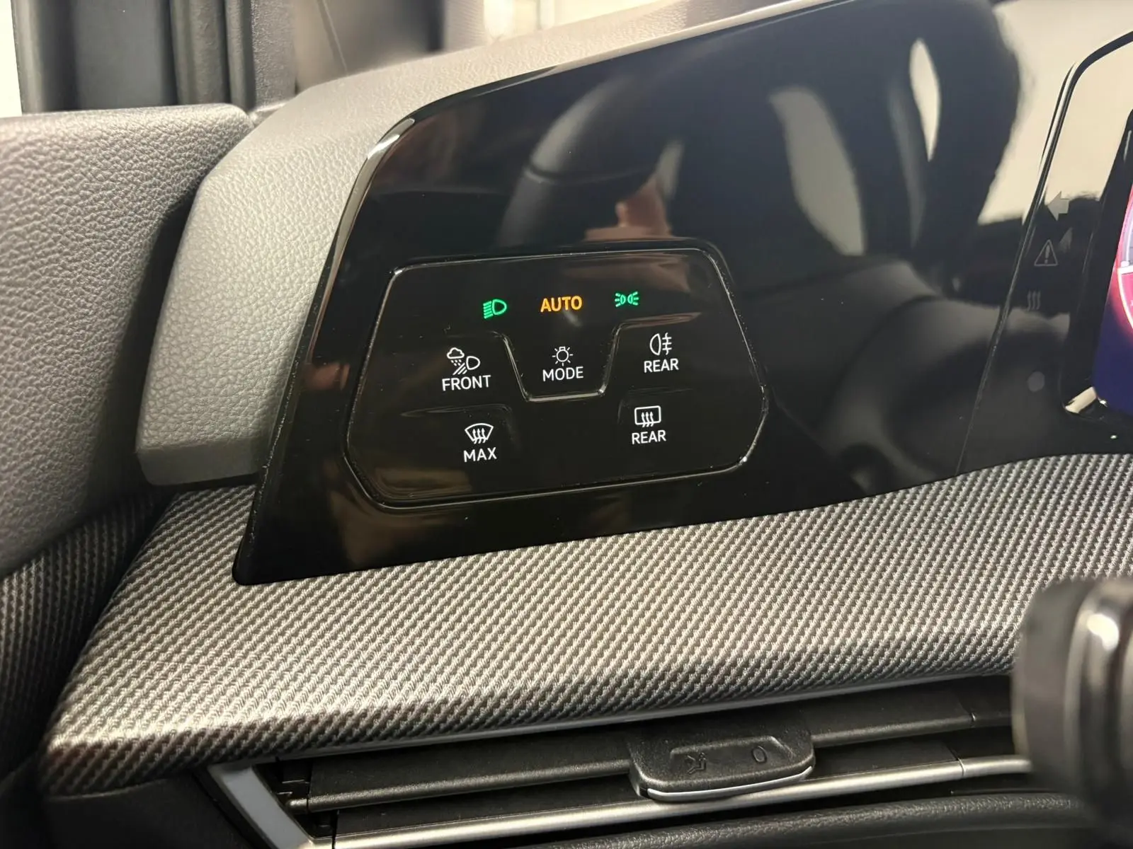 Détail du tableau de bord avec commandes d'éclairage et finition carbone dans une Volkswagen Golf Gris Dauphin 2025.