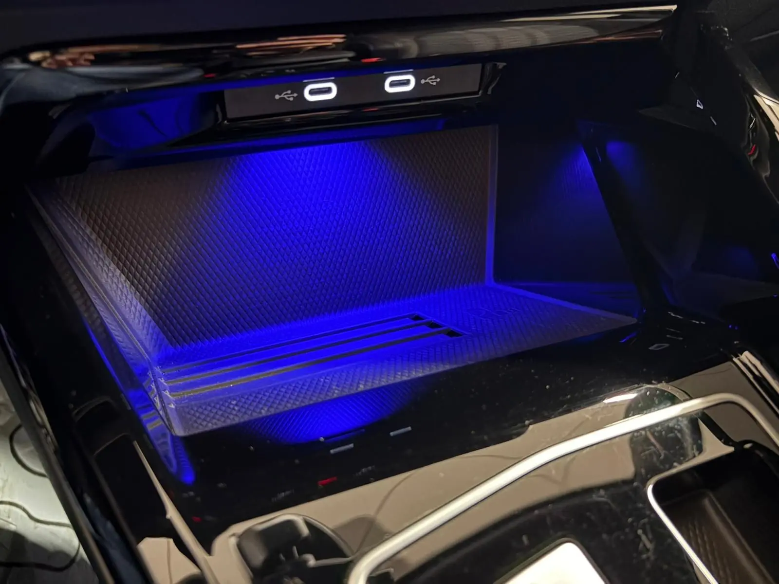 Gros plan sur le rangement central éclairé en bleu avec ports USB-C dans une Volkswagen Golf Gris Dauphin 2025.