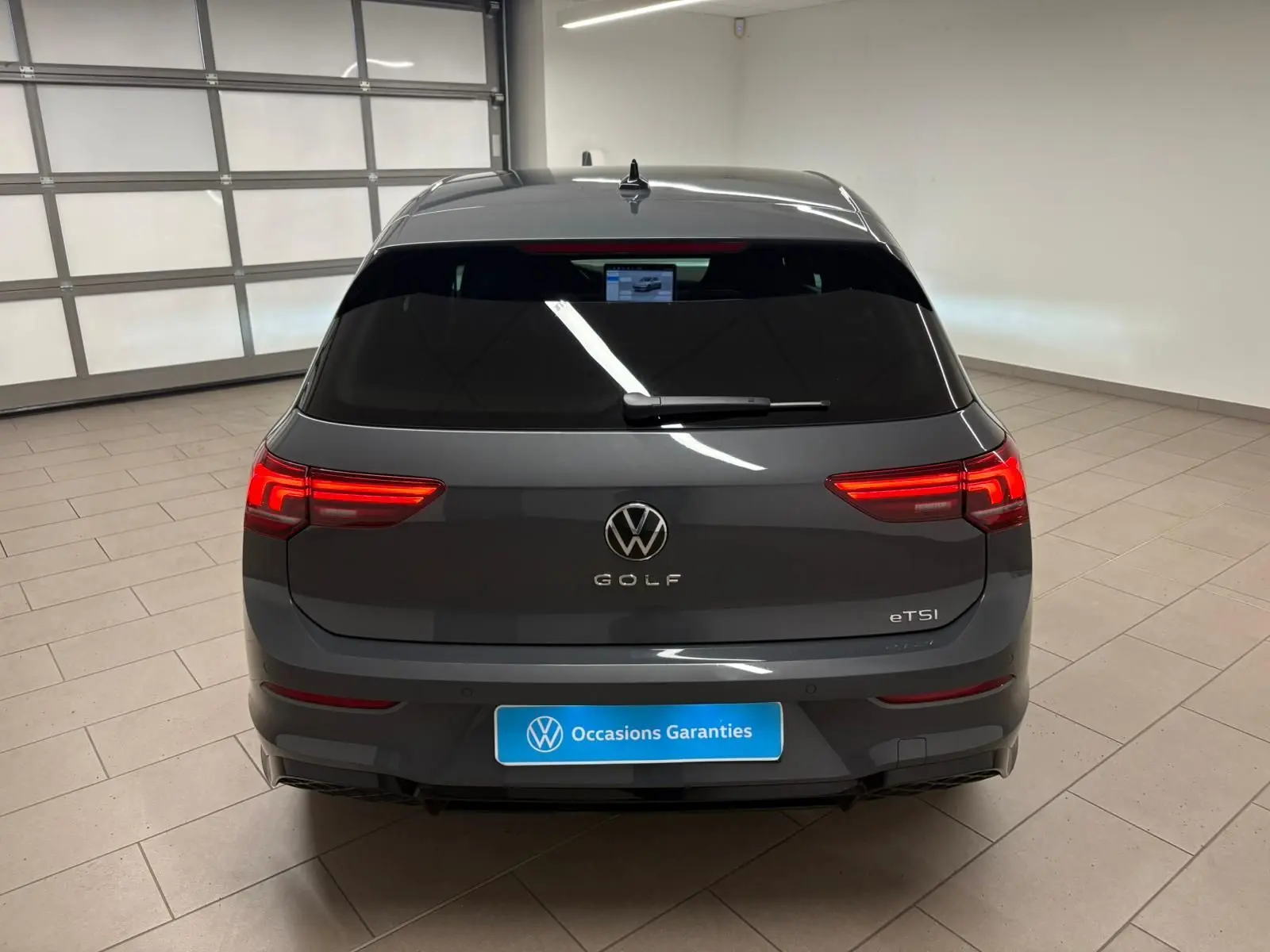 Vue arrière d'une Volkswagen Golf 1.5 eTSI gris dauphin avec feux LED allumés dans un garage.