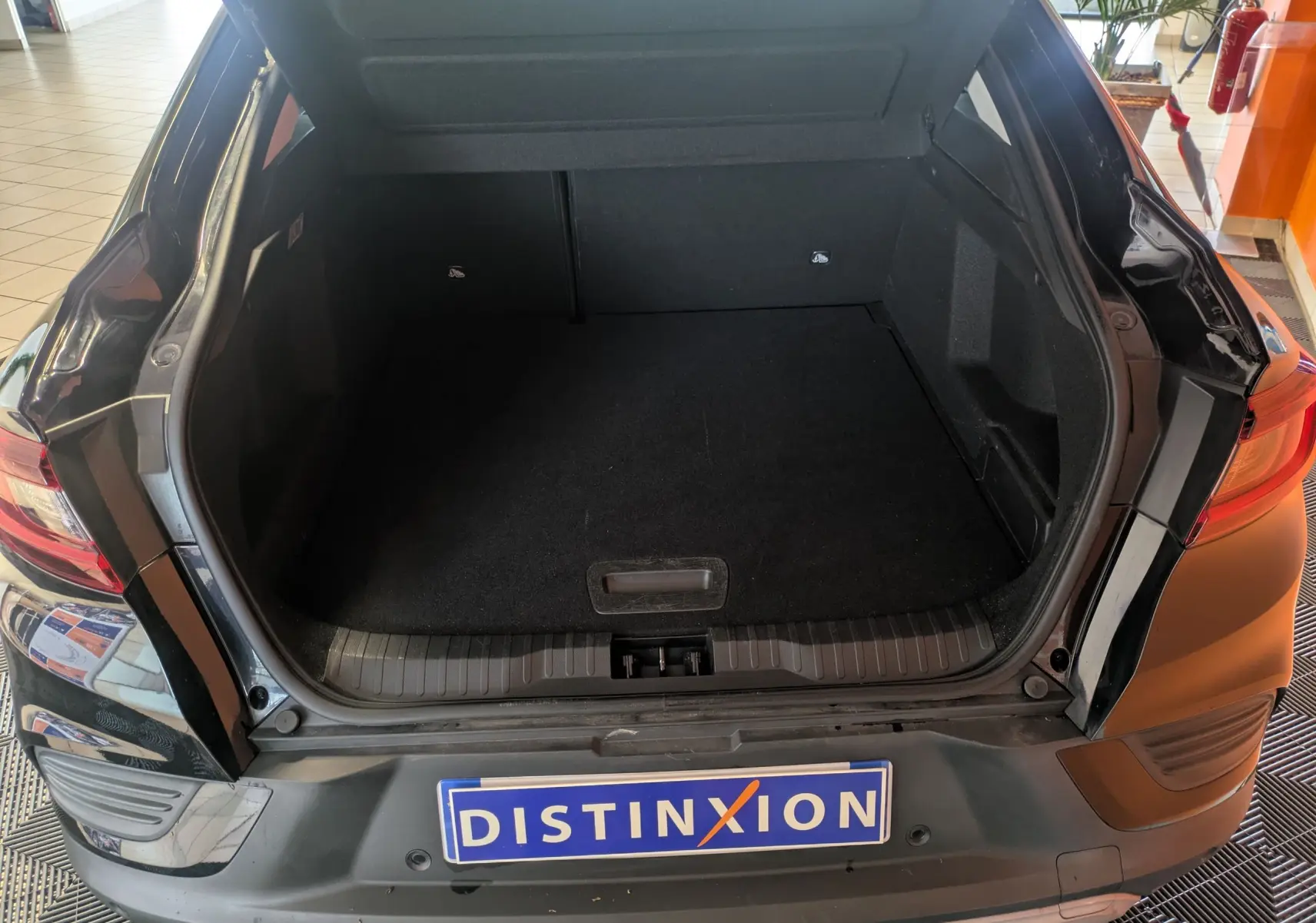 Coffre ouvert vu de l'arrière d'une Renault Arkana noire 2023, mettant en valeur l'espace de chargement vide.