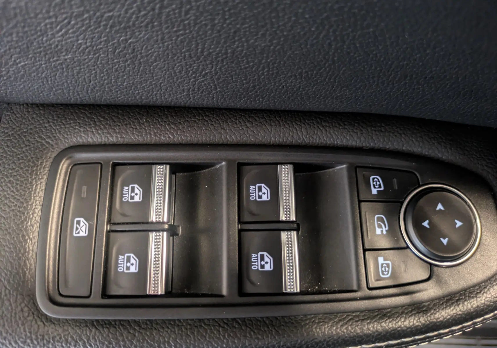 Gros plan sur les commandes de lève-vitres et réglages des rétroviseurs côté conducteur du Renault Arkana noir 2023.