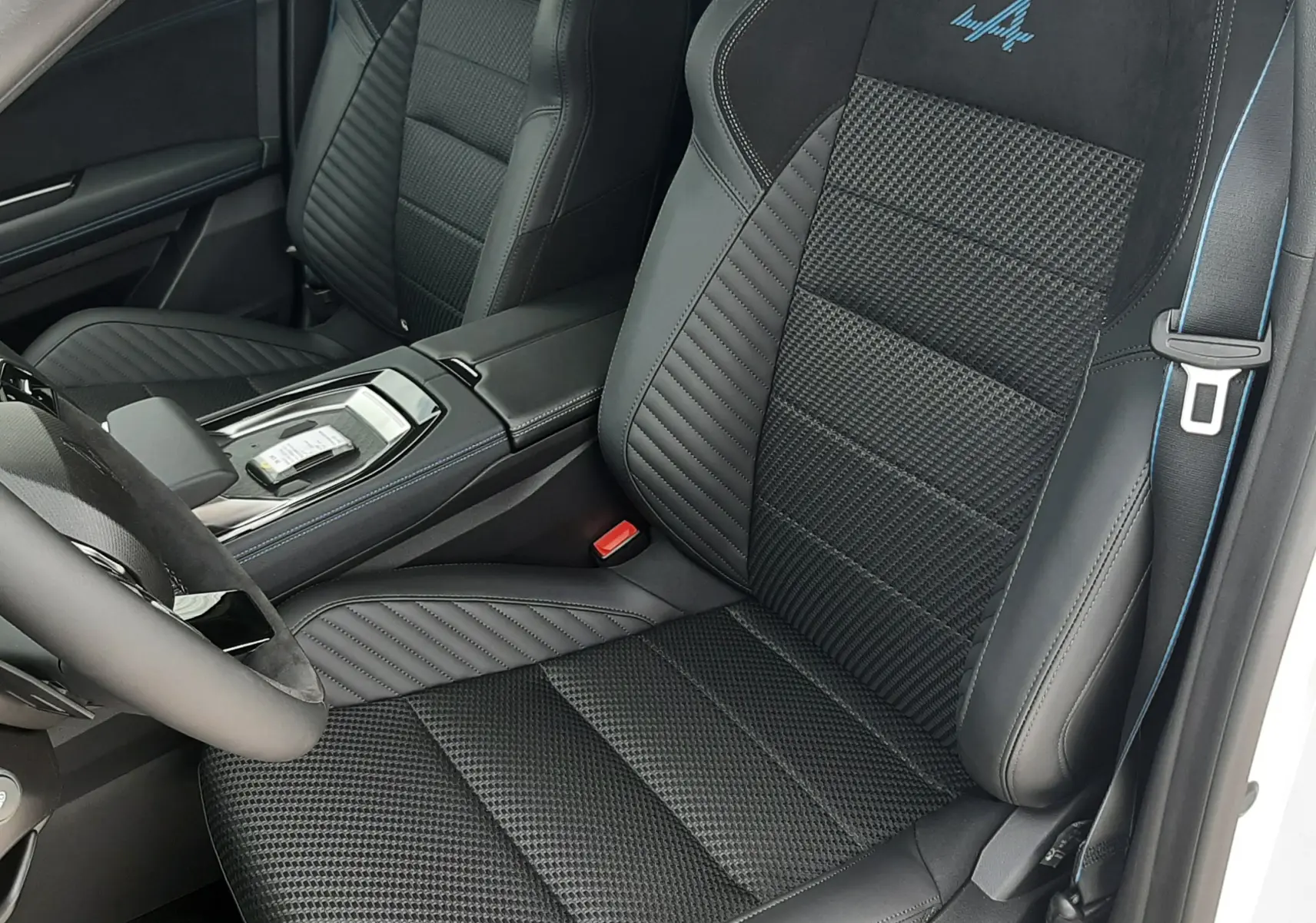 Vue intérieure côté conducteur du Renault Austral Esprit Alpine 2026, sièges noirs mixte Alcantara avec logo Alpine bleu brodé.