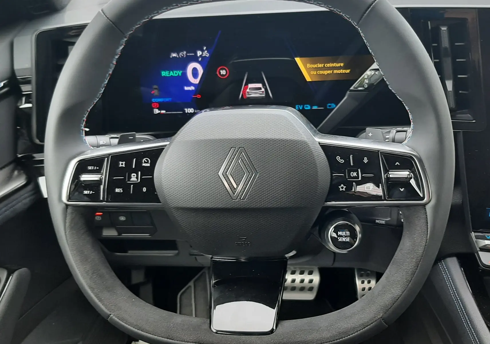 Vue intérieure centrée sur le volant multifonction du Renault Austral hybride avec tableau de bord numérique lumineux.