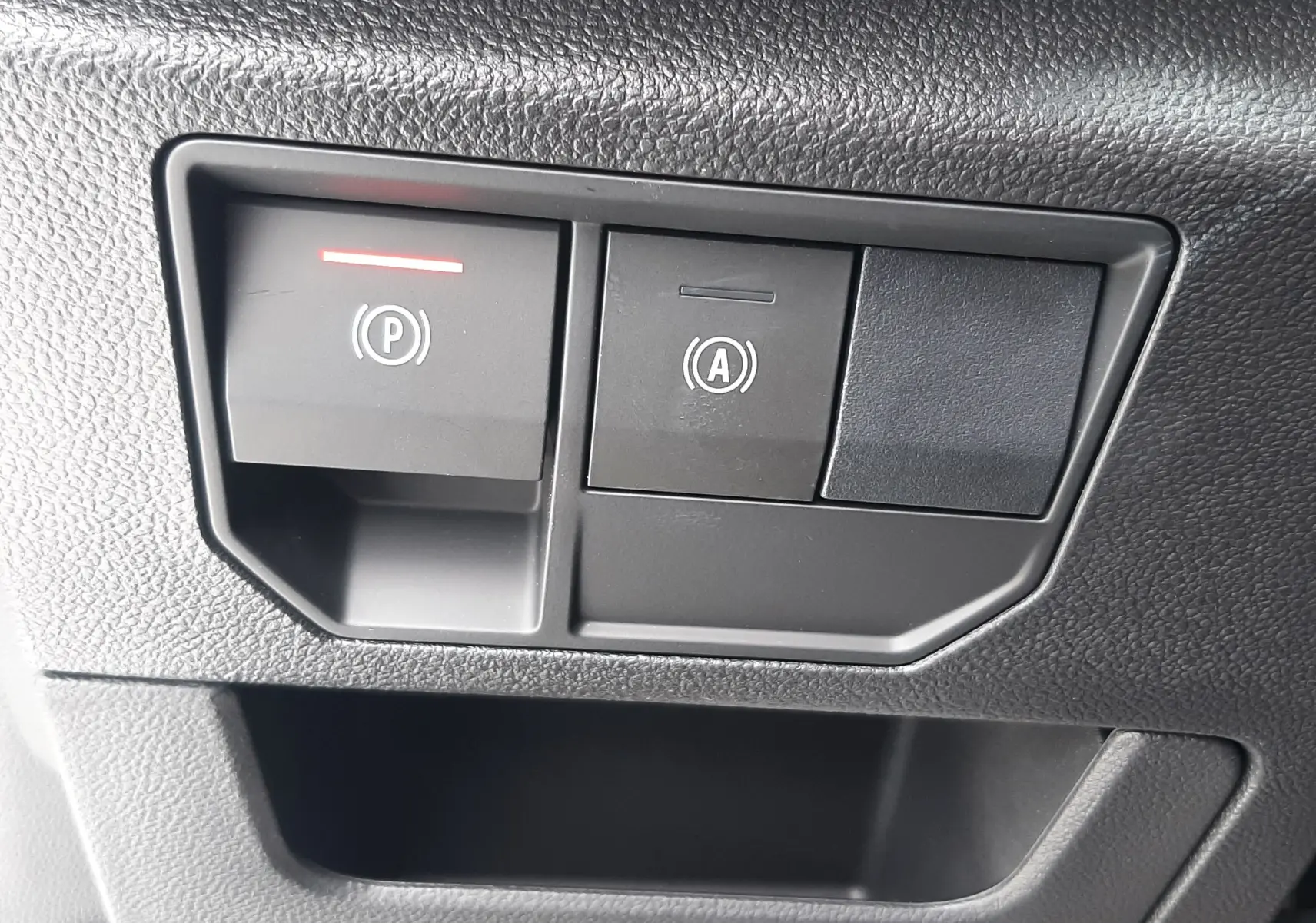 Gros plan sur les commandes noires du frein de parking électrique et de l'arrêt automatique du moteur dans un Renault Austral blanc nacré.
